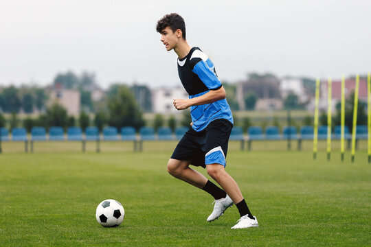 A young soccer player practicing his skills on a field, dribbling the ball with precision and focus.